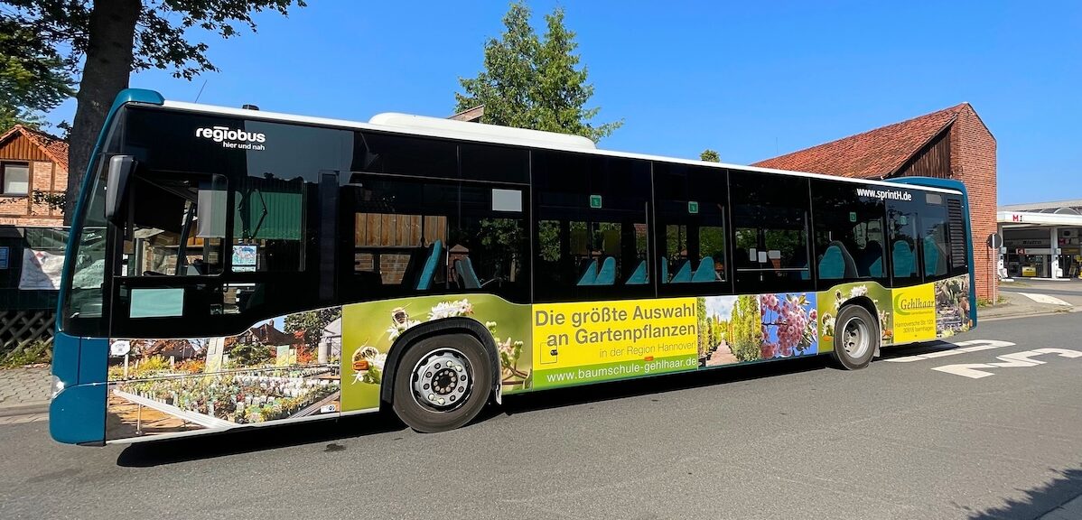 An einer Haltestelle in Fuhrberg (Region Hannover) steht ein Bus in der 30er Zone. Der Bus ist mit bunten Pflanzen und Blumen beklebt. Und man sieht den Schriftzug "Die größte Auswahl an Pflanzen in der Region Hannover".